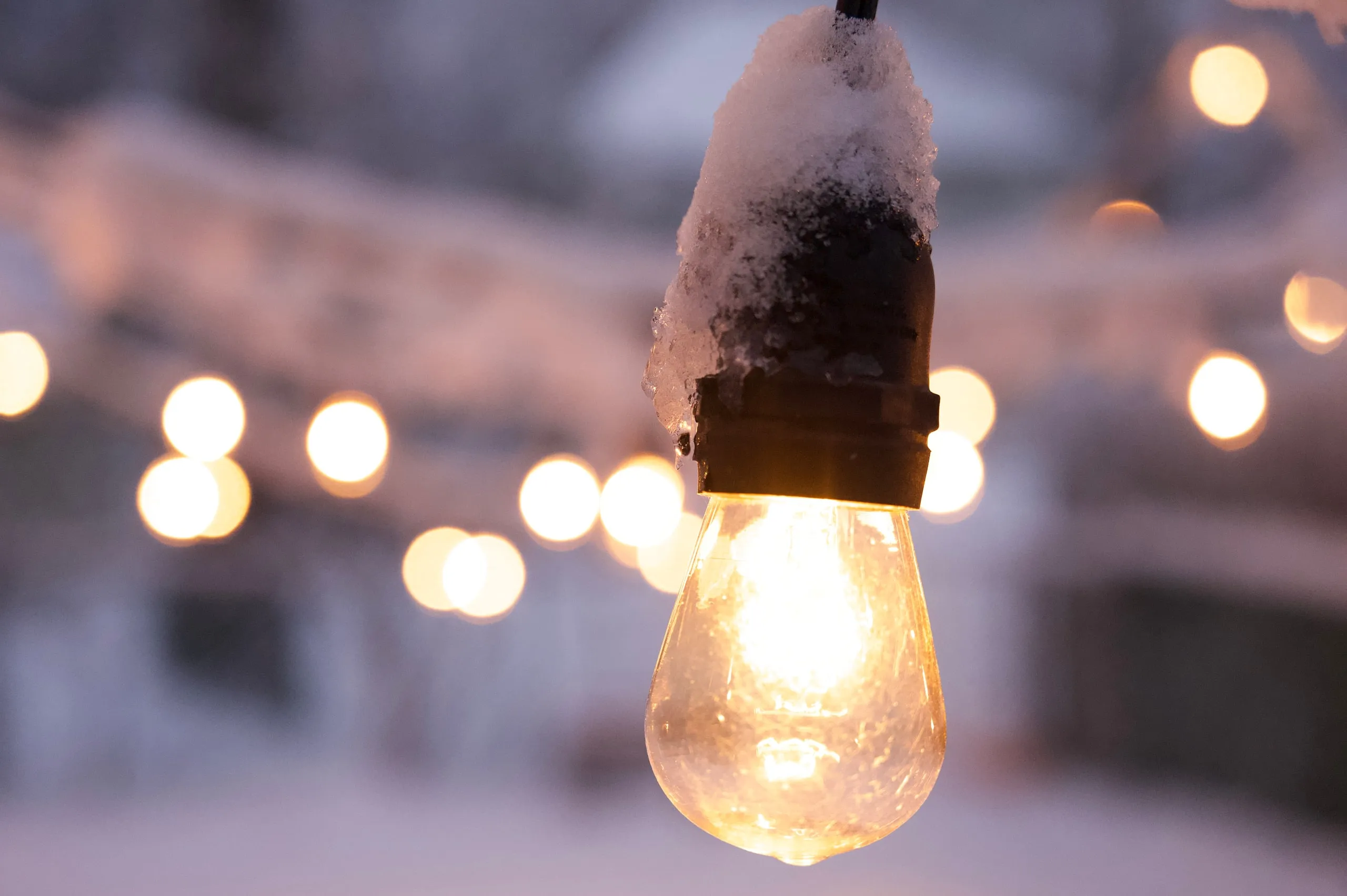 A glowing vintage light bulb in front of a blur of string lights
