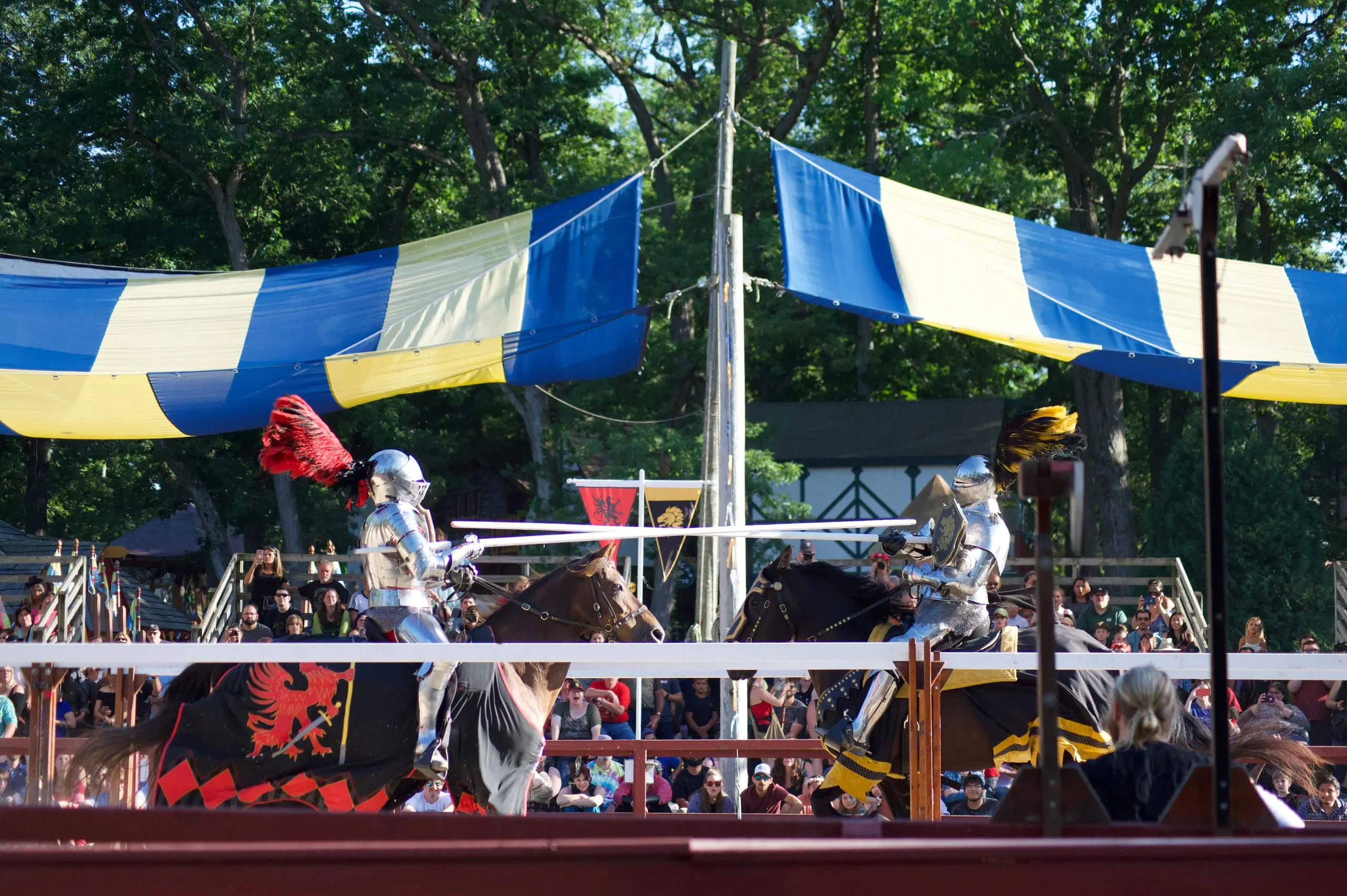 Knights jousting at a Renaissance faire under blue and yellow banners
