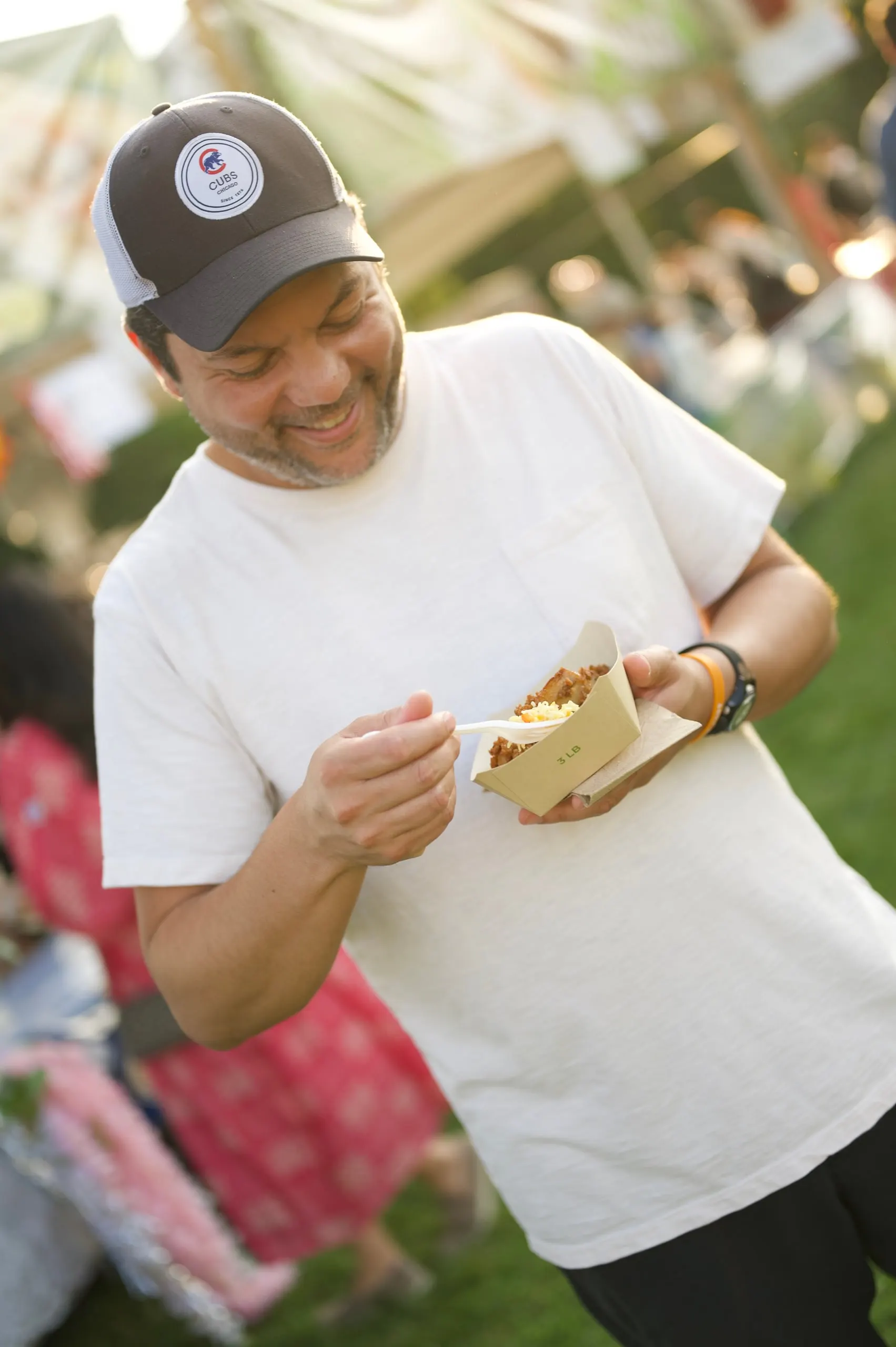 A smiling man in a cap enjoying festival food
